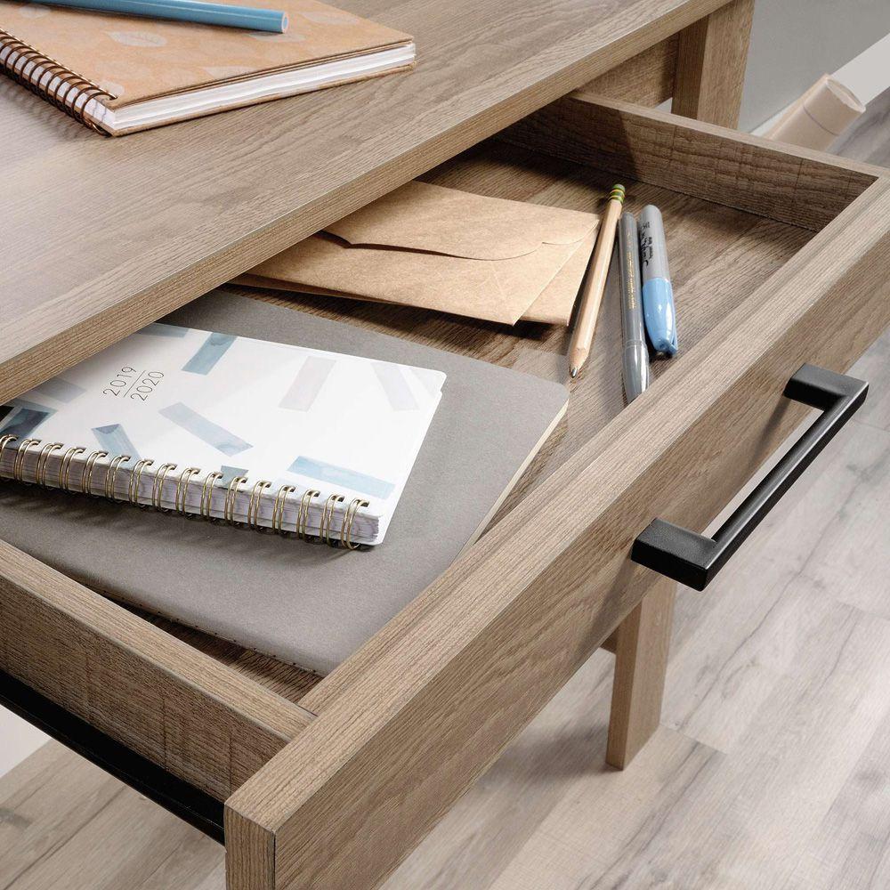 a wooden desk with a book, notebook, and pen