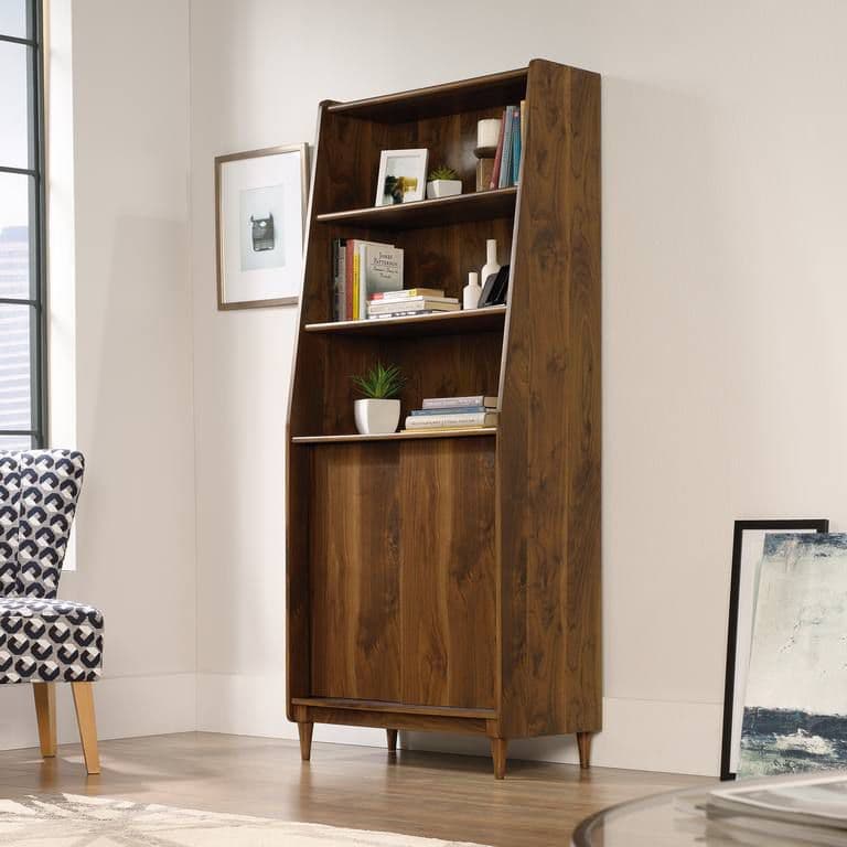 a wooden bookcase in a living room next to a chair