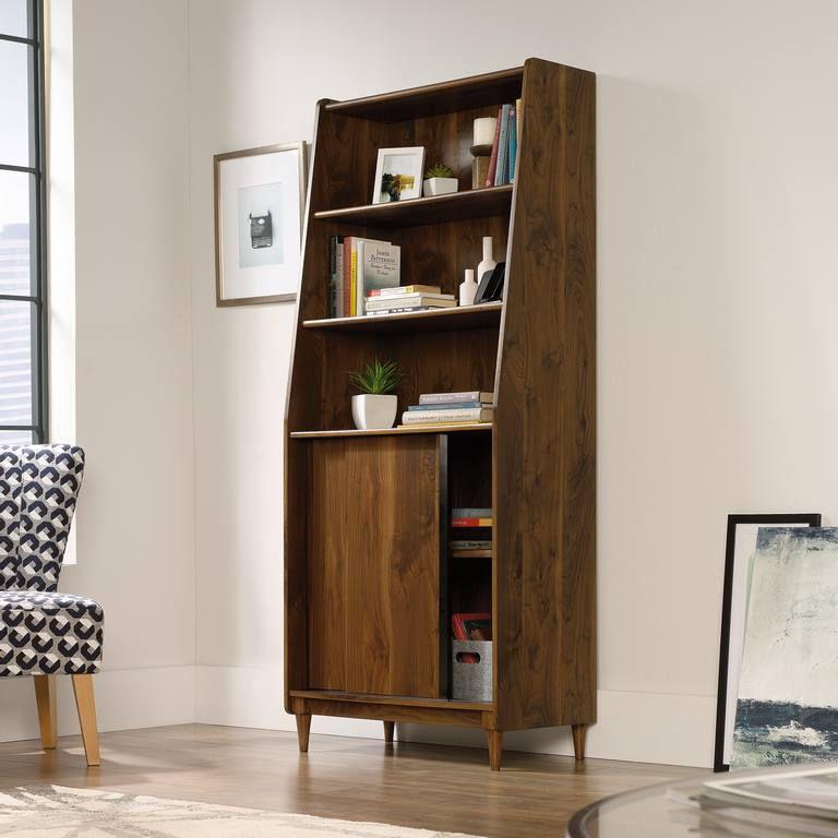 a wooden bookcase in a living room next to a chair