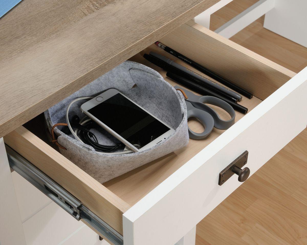 an open drawer with a cell phone and a pair of scissors