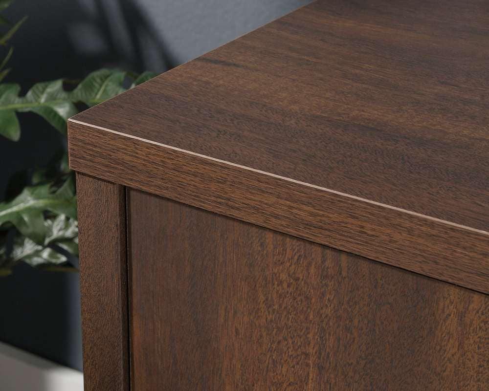 a wooden desk with a plant in the background