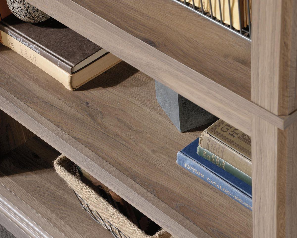 a book shelf with books and a basket on top of it