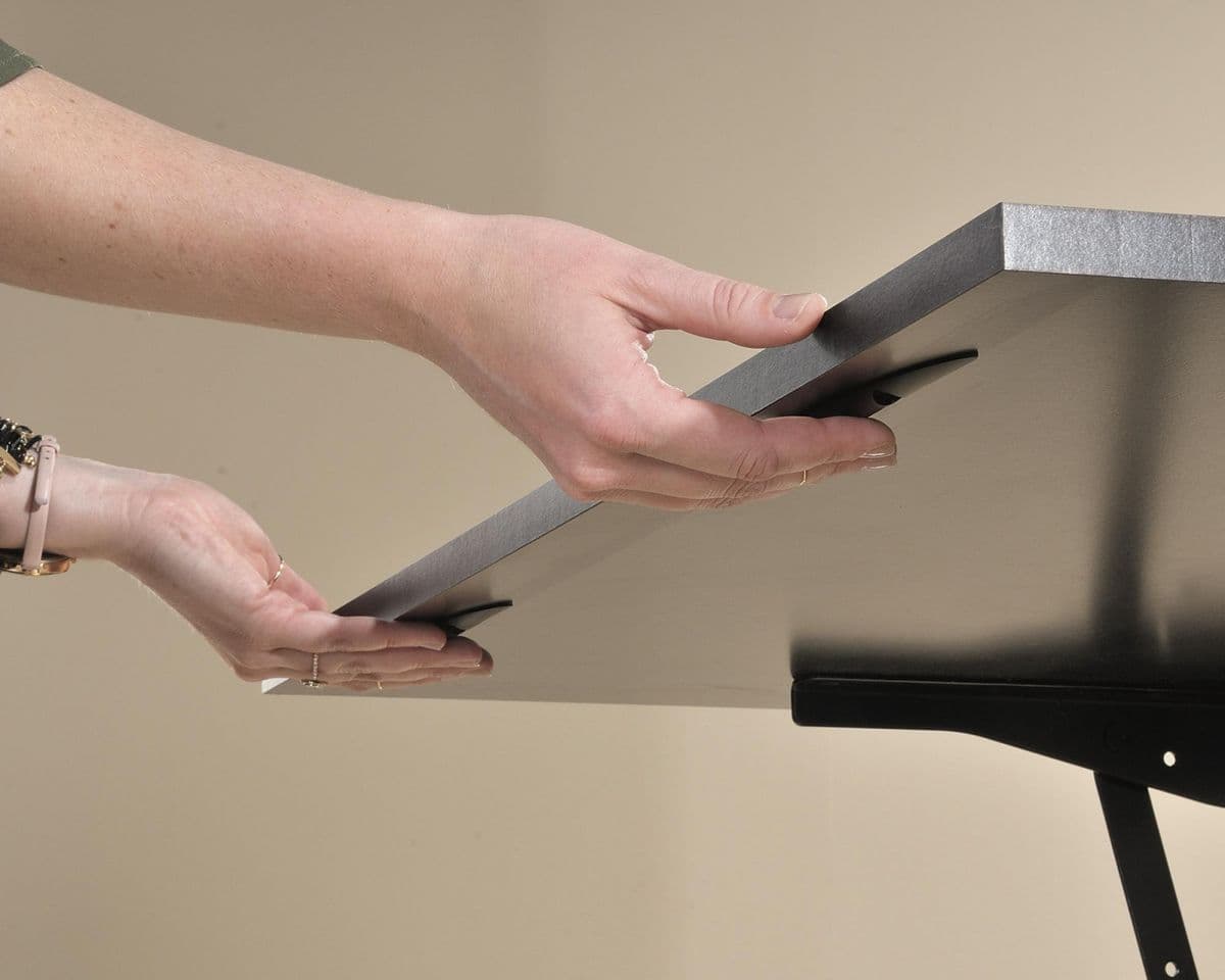 a person holding a piece of metal on top of a table