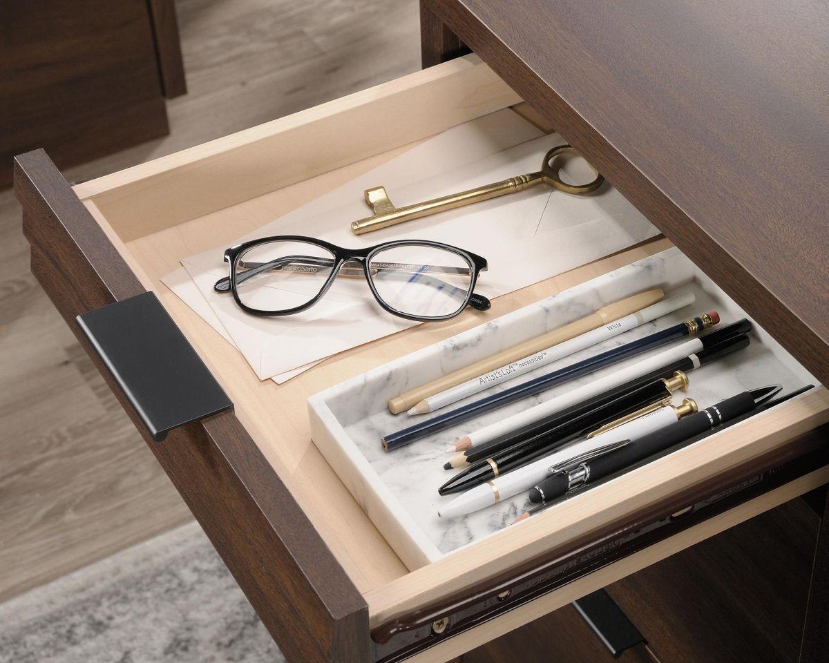 a drawer with a pair of glasses, pens, and a pen holder